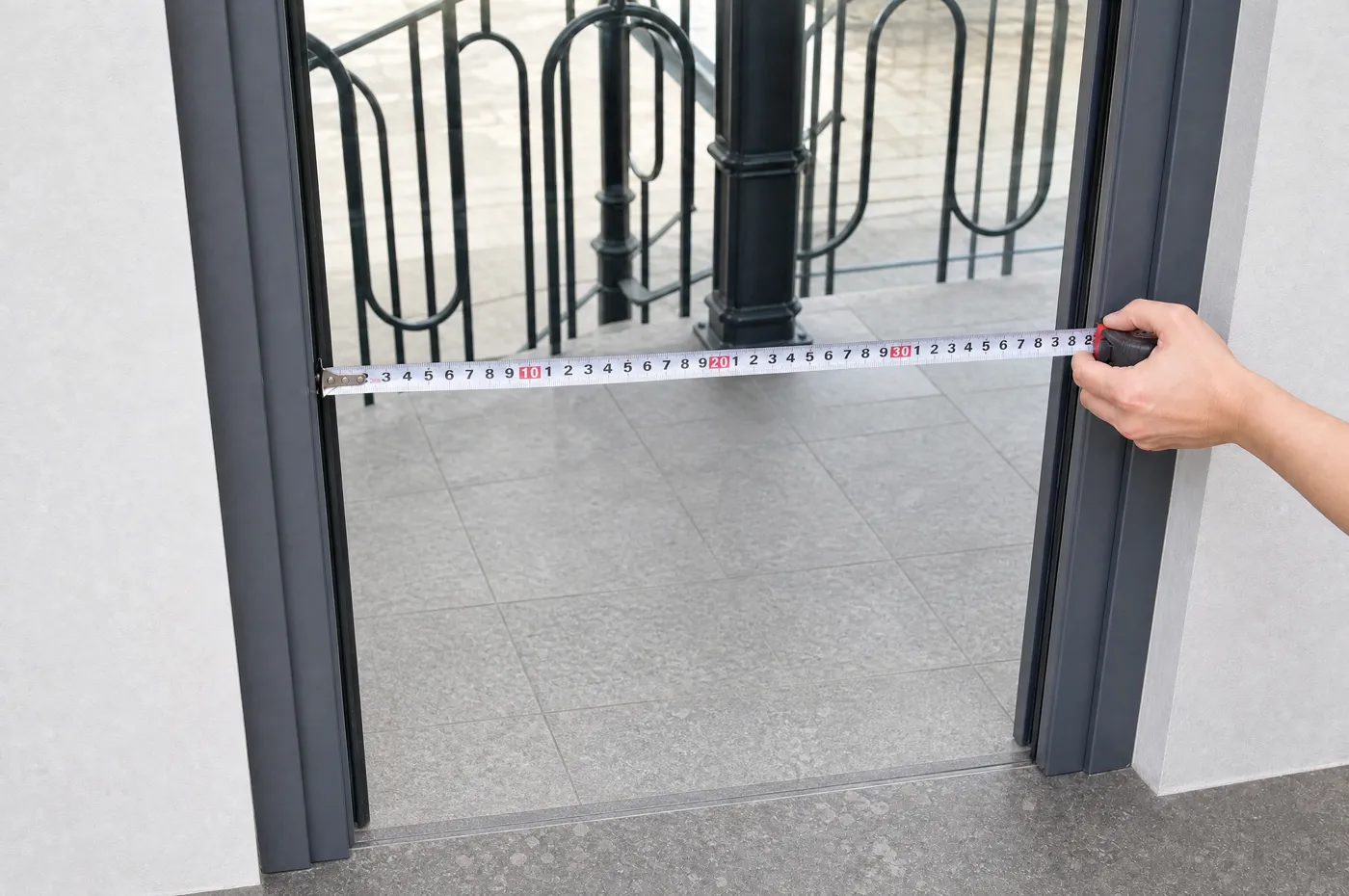 Cinta métrica tensada en horizontal en el hueco libre de la puerta, del borde interior del marco a la izquierda al de la derecha